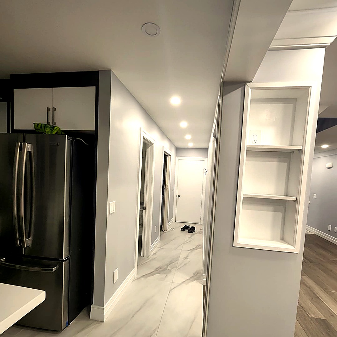 Renovated hallway with marble-look tile flooring, built-in shelving and pot lights