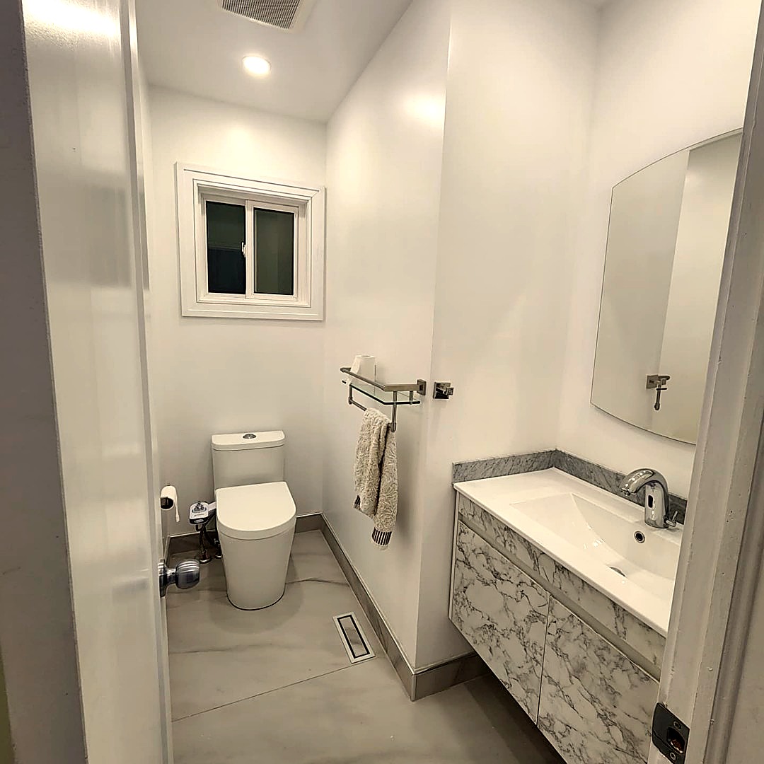 Compact white bathroom with marble-look vanity, toilet and chrome fixtures
