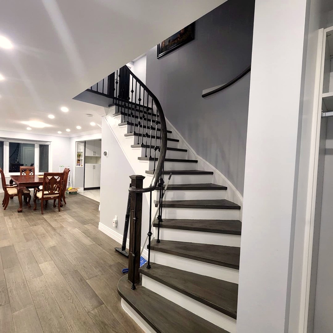 Curved open-rise staircase with dark hardwood treads and iron balusters