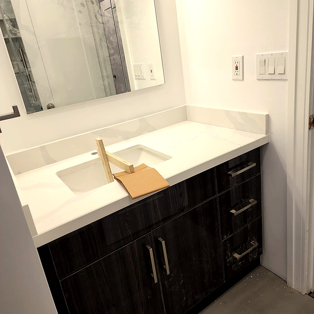 Bathroom vanity with dark wood cabinets and white marble-look countertop