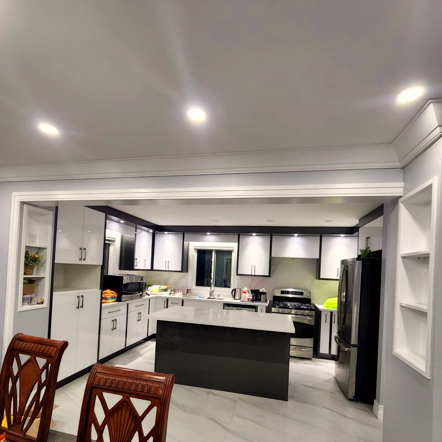 High-gloss white and charcoal kitchen with quartz island and under-cabinet lighting