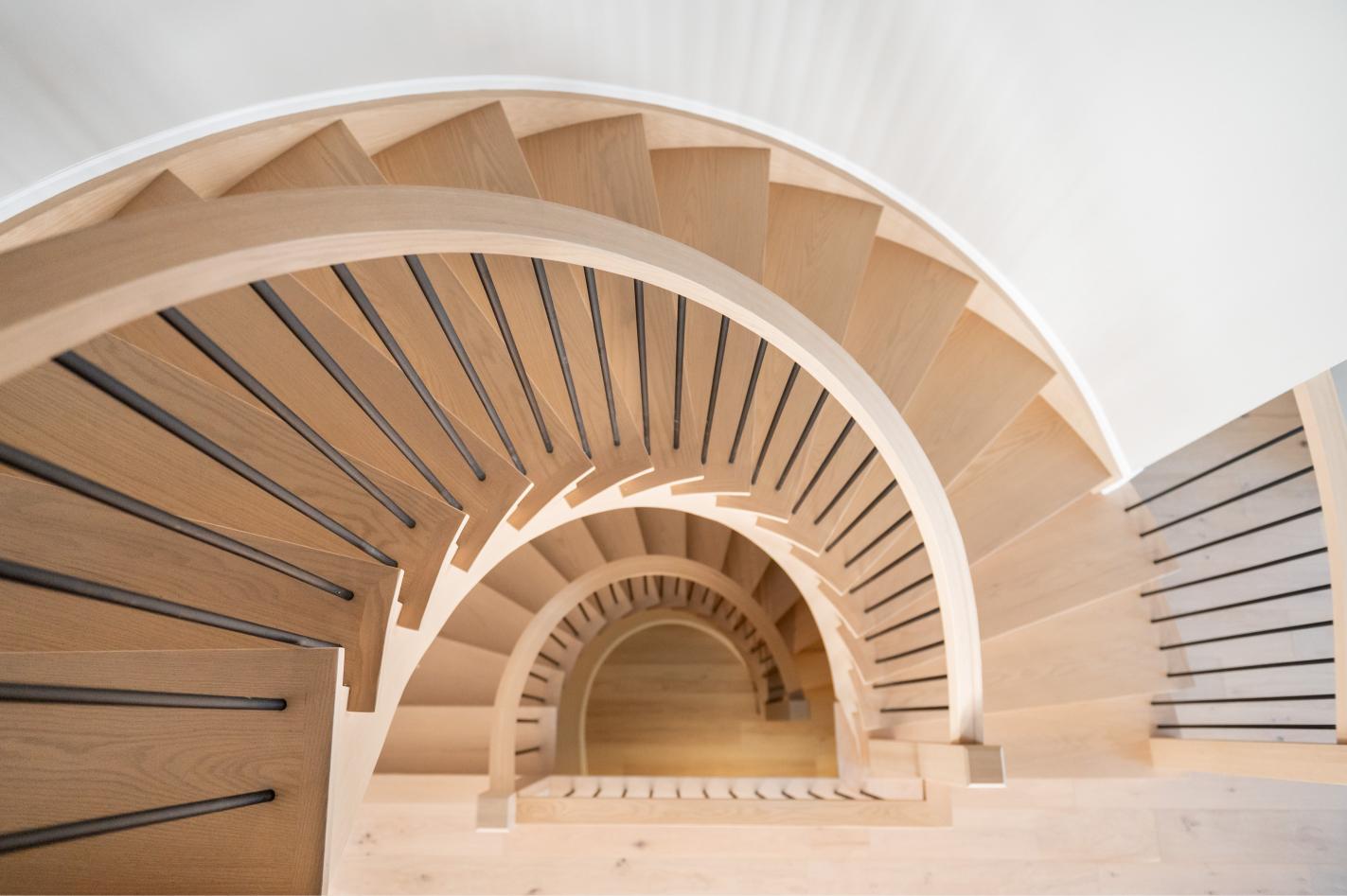 Sculptural curved staircase in white oak with black metal spindles in Port Perry, Ontario