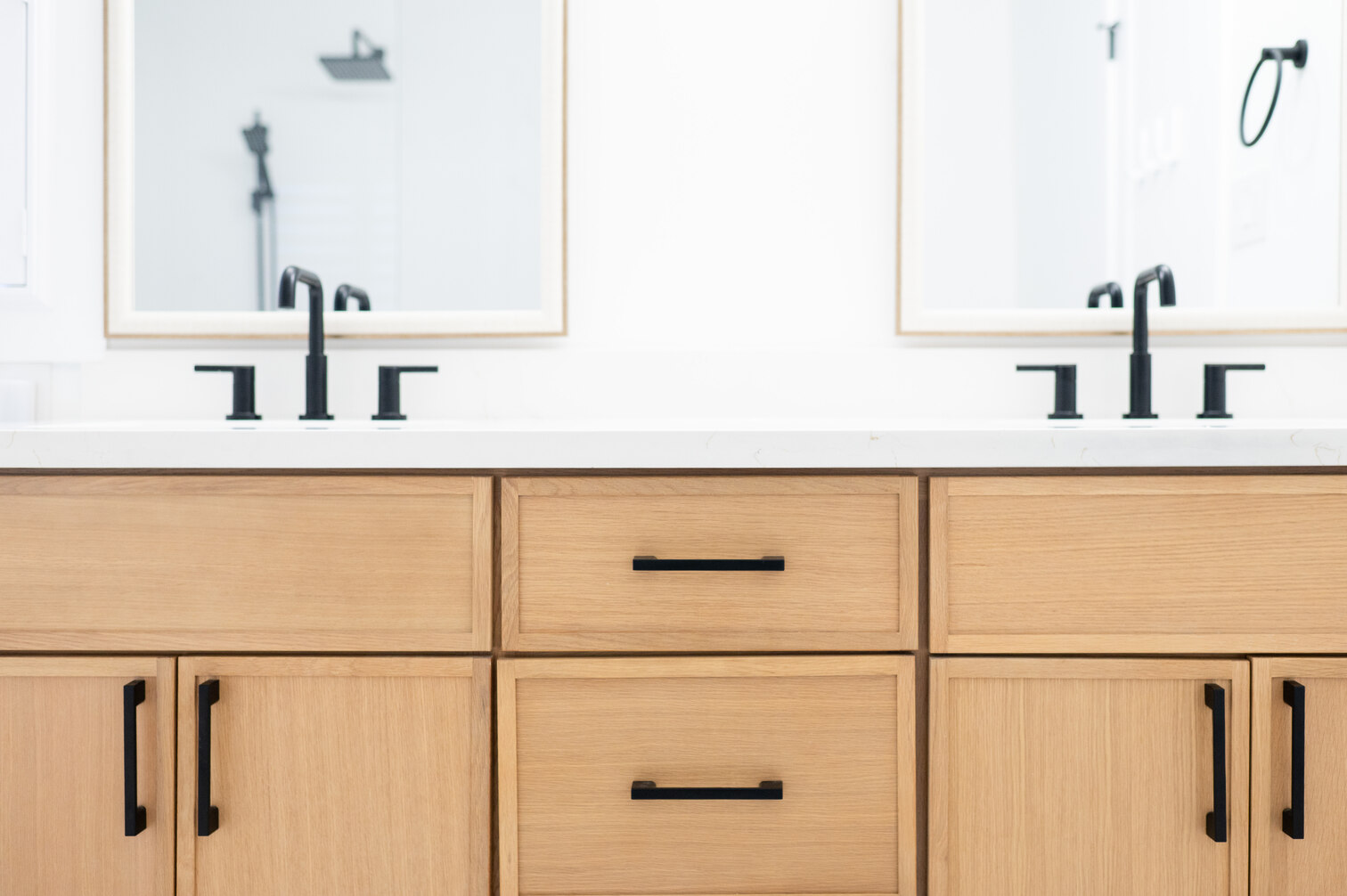 White oak double vanity with matte black faucets in a renovated bathroom