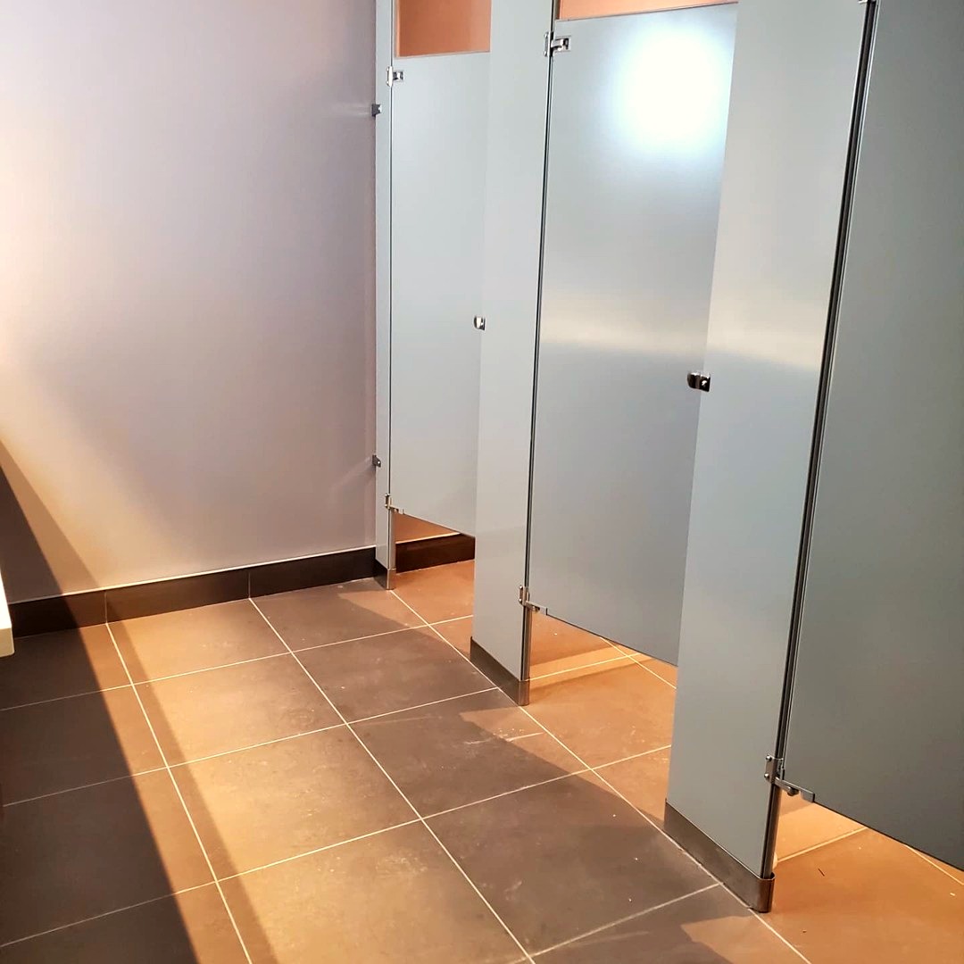 New commercial washroom with privacy stall partitions and tiled flooring