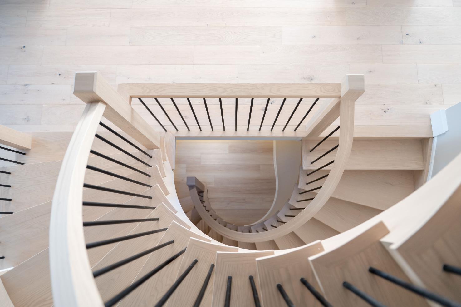 Overhead view of a curved white oak staircase with black spindles