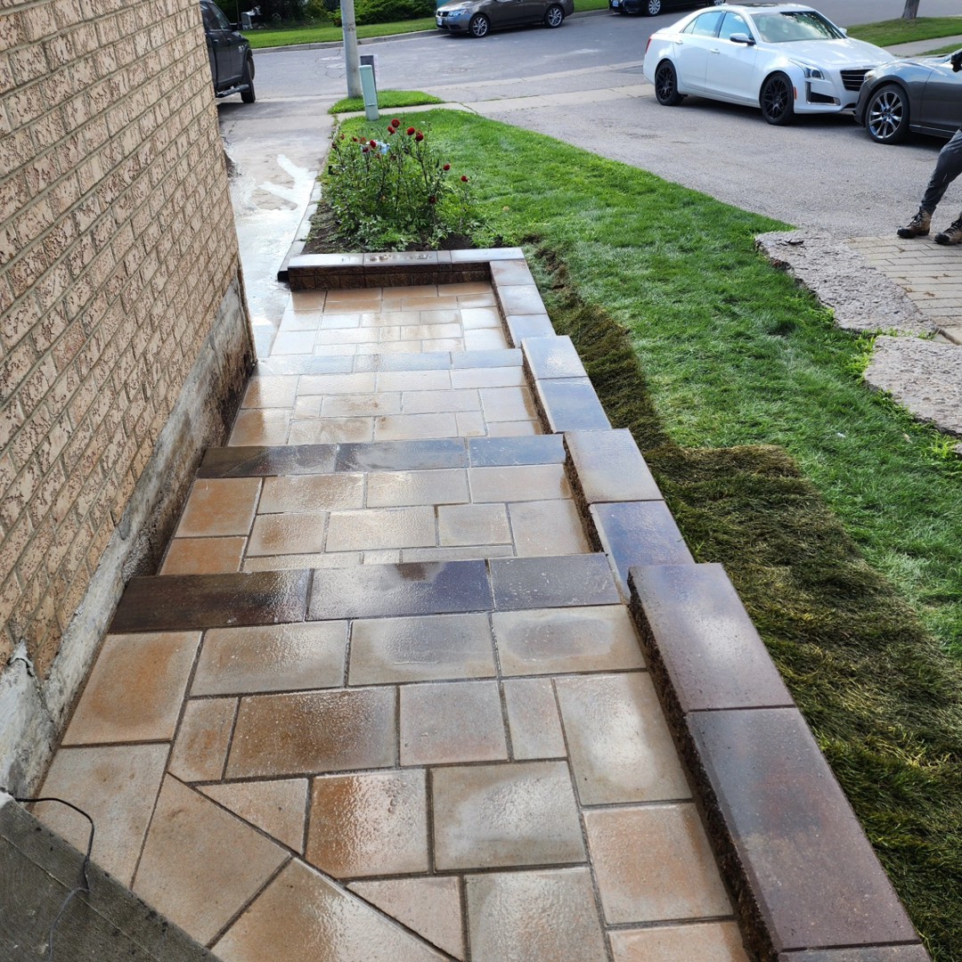 Flagstone walkway with stone edging along the side of a brick home