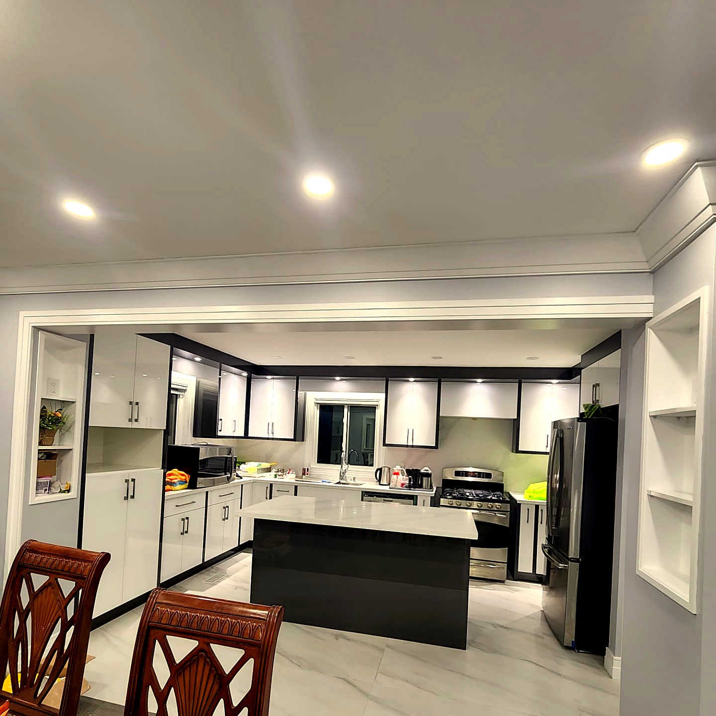 Modern white and black kitchen with quartz island and stainless steel appliances