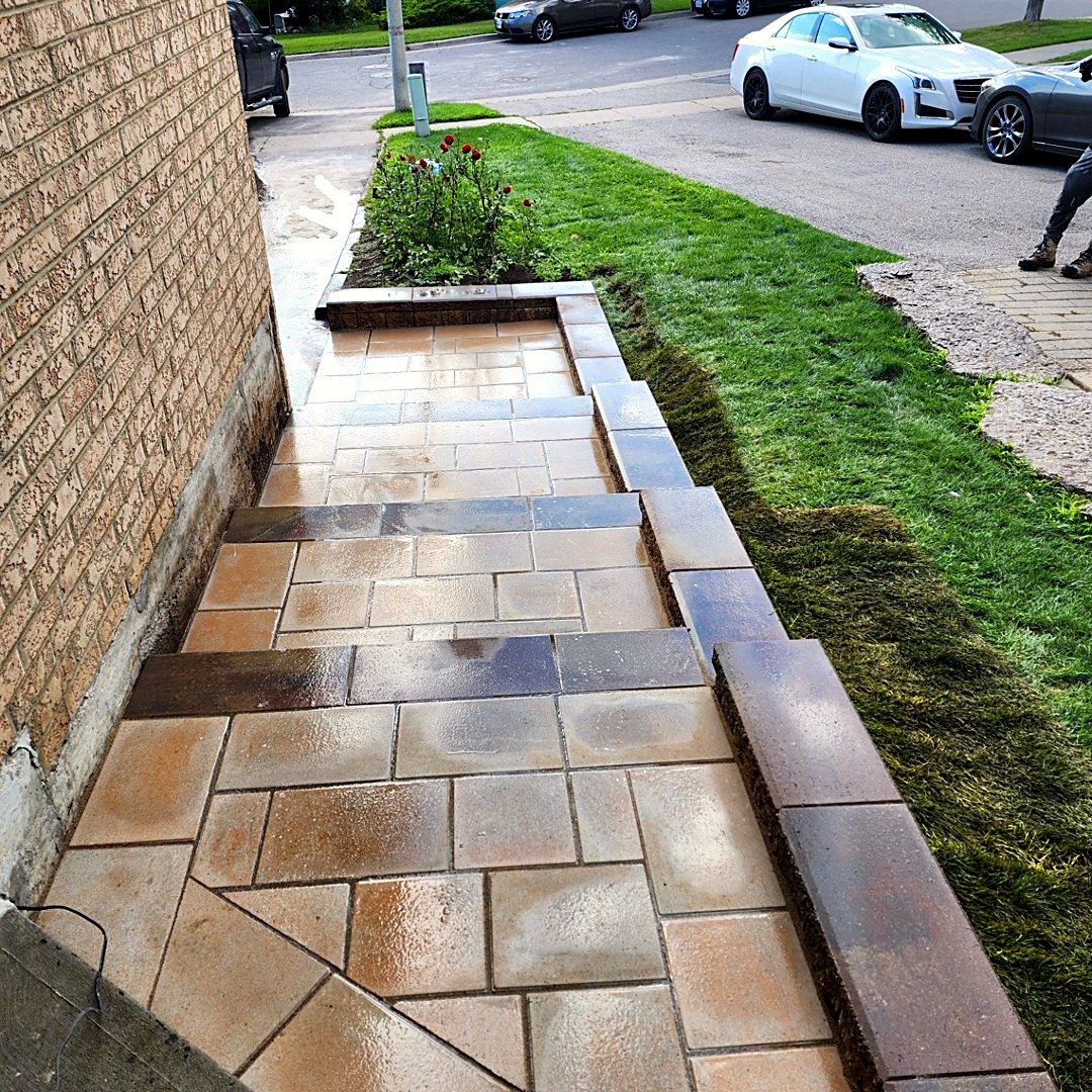 Paver walkway and steps with garden bed along a brick home